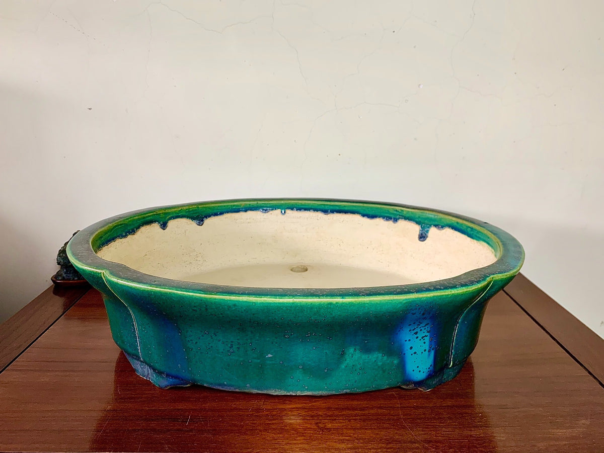 A glazed ceramic pot with a vibrant green rim and a cream-colored interior.