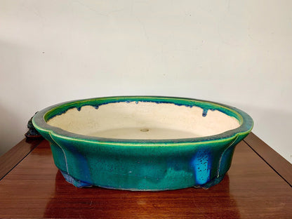A glazed ceramic pot with a vibrant green rim and a cream-colored interior.