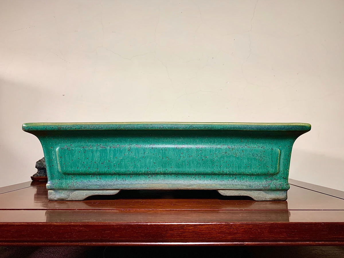 A long, rectangular glazed pot in teal with a speckled finish and raised edges.