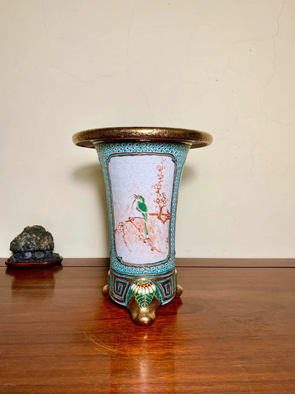 A tall, flared ceramic pot with a gold rim, turquoise border, and painted bird on a light blue background.