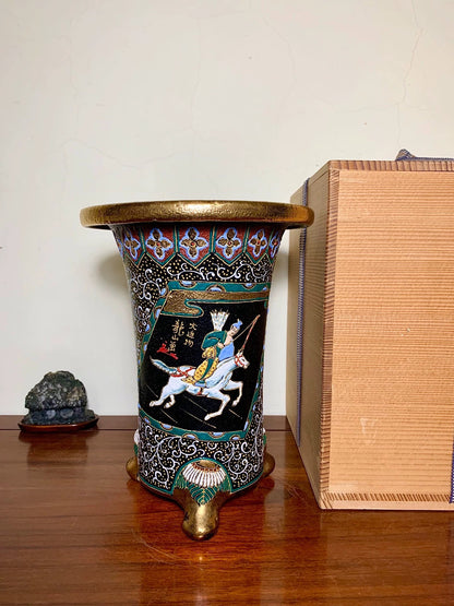 Black enamel pot with gold rim and foot, decorated with a white horse and rider scene.