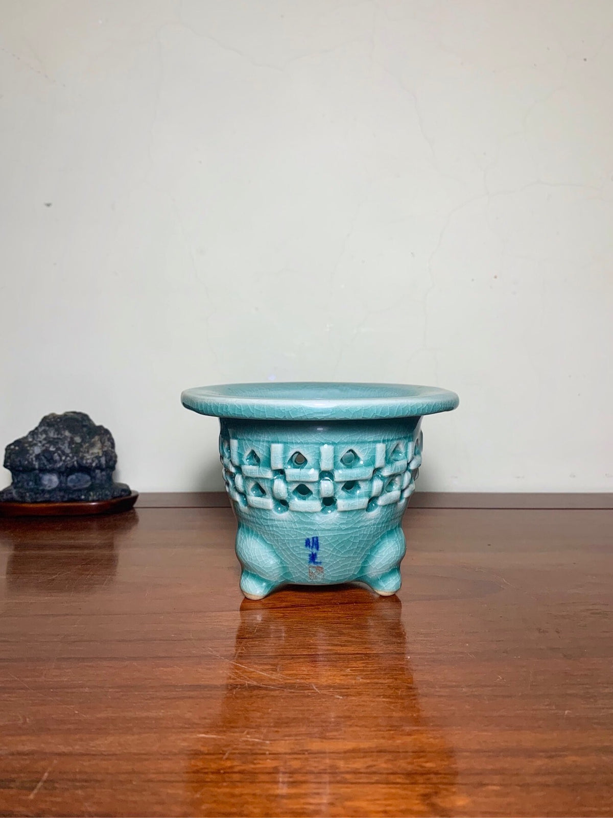 Turquoise glazed ceramic pot with geometric lattice pattern and three feet, matte finish.