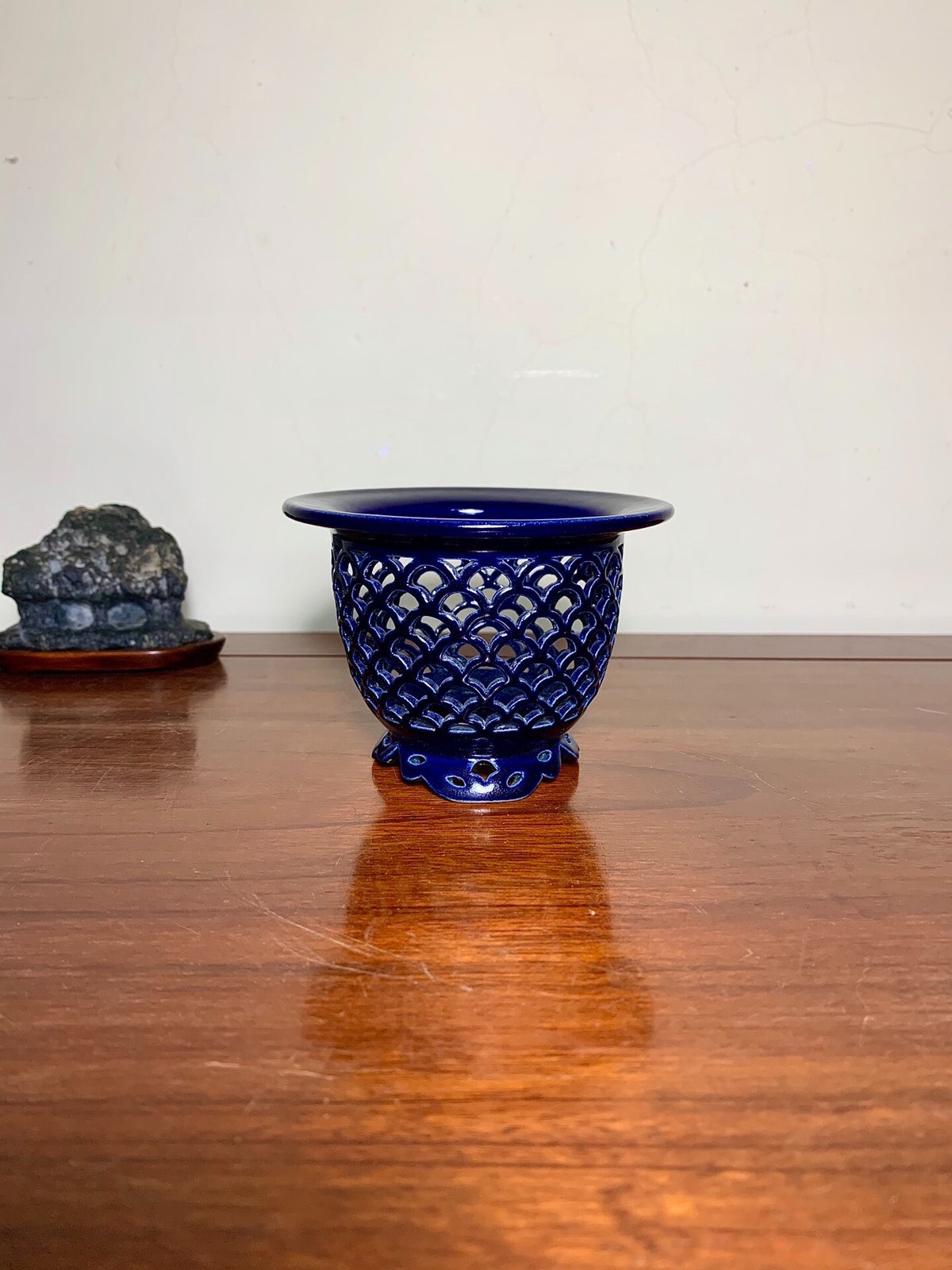 A glossy cobalt blue ceramic pot with a scalloped rim and intricate lattice pattern.