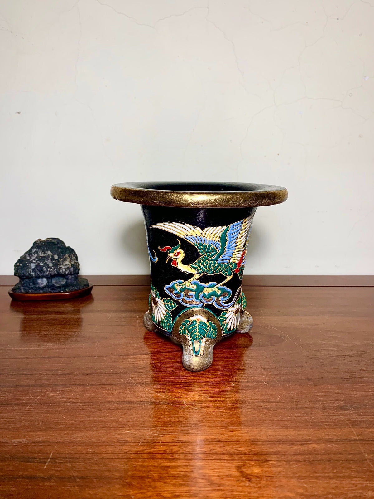 Black glazed pot with gold rim, three feet, and colorful crane decoration on clouds.