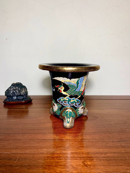 Black glazed pot with gold rim, three feet, and colorful crane decoration on clouds.