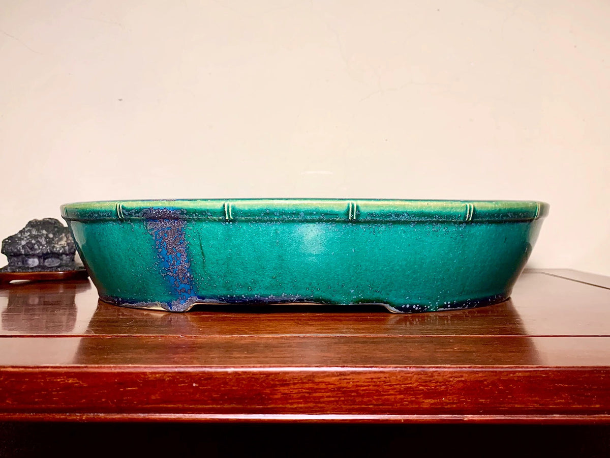 A glossy teal glazed rectangular pot with a blue drip mark on its side.
