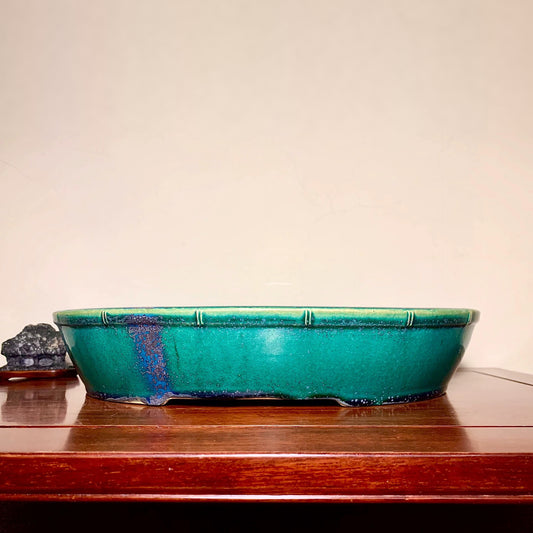 A glossy teal glazed rectangular pot with a blue drip mark on its side.