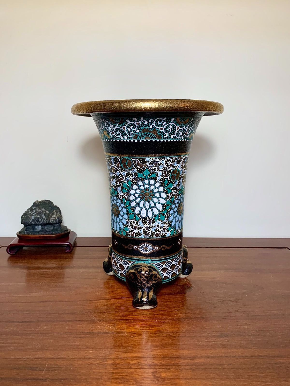 A tall, flared pot with a gold rim, blue and white floral patterns, and three elephant-head feet.