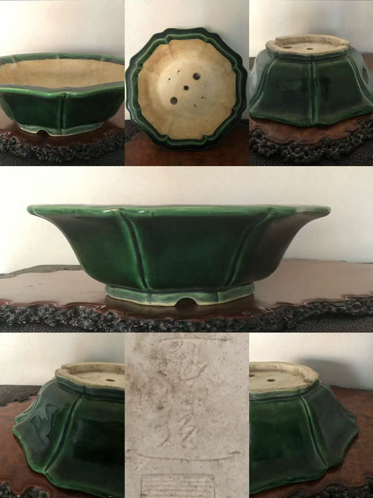 A glossy green glazed pot with flared sides and a scalloped rim, showing its base and drainage holes.