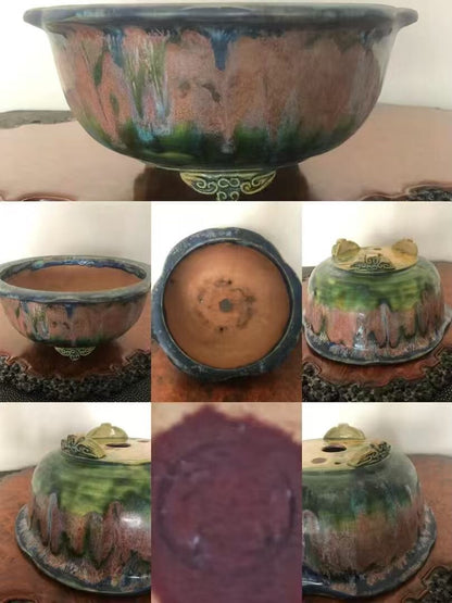 A glazed ceramic pot with a wide rim, mottled green and brown glaze, and a decorative foot.