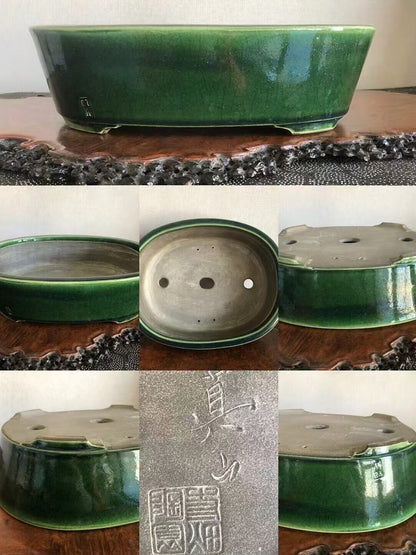 A glossy green ceramic bonsai pot with three drainage holes and a square maker's mark.