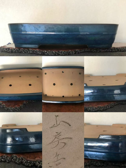 Dark blue glazed square pot with unglazed beige interior, six drainage holes, and faint Japanese characters.