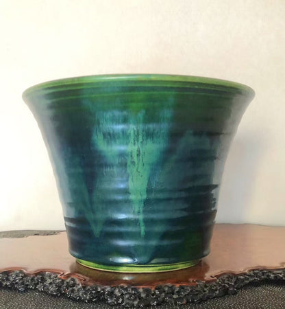 A glossy green glazed pot with darker green streaks and a flared rim.