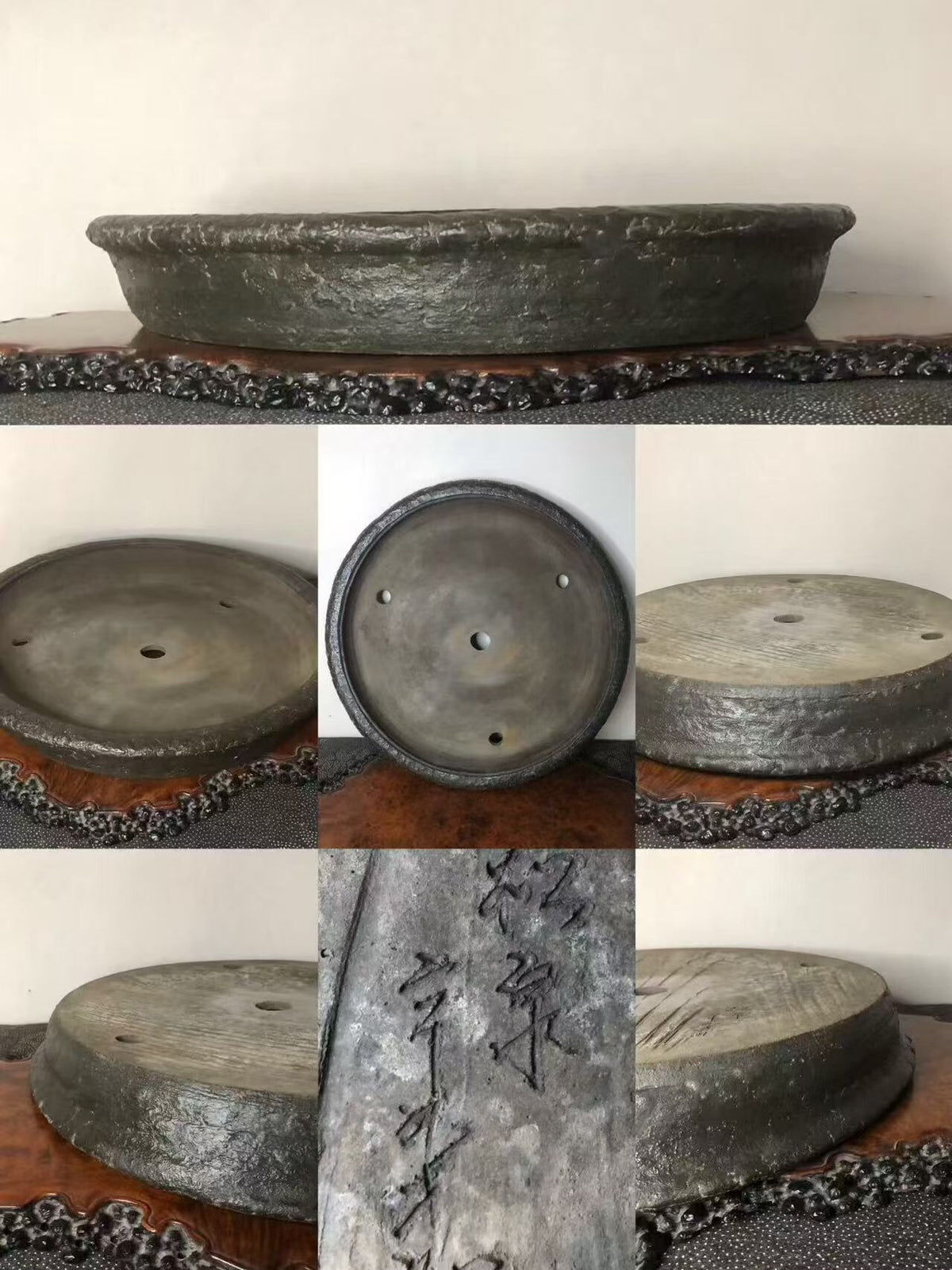 Dark grey, shallow, unglazed ceramic pot with three drainage holes and carved characters on its side.