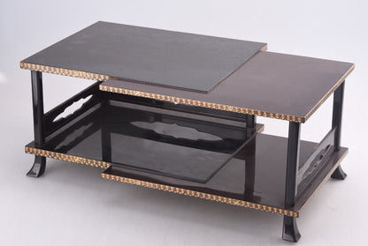 Black lacquered two-tiered table with gold inlaid edges and glass shelves.