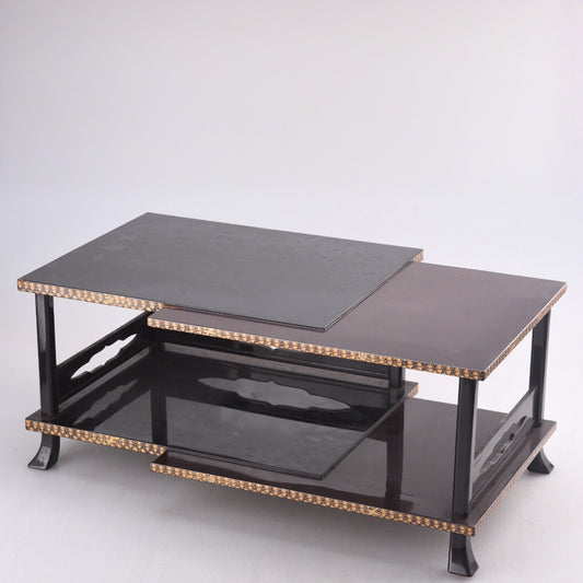 Black lacquered two-tiered table with gold inlaid edges and glass shelves.
