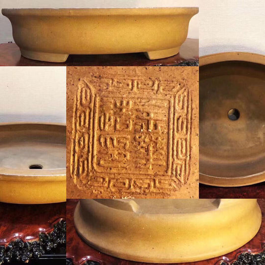 A yellow glazed ceramic bonsai pot with a square carved mark on its base.