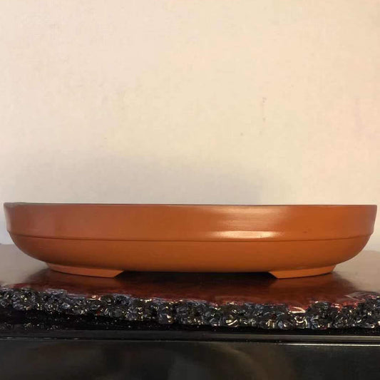 A terracotta bonsai pot with a matte finish, featuring a square mark and drainage holes.