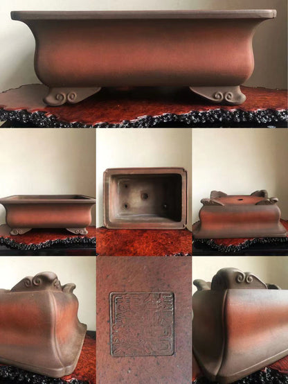 A reddish-brown glazed rectangular pot with four ornate feet and an embossed square seal on its base.