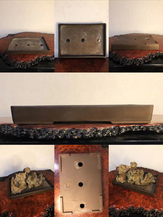 A rectangular, matte, dark brown ceramic bonsai pot with three drainage holes and a rough, textured base.