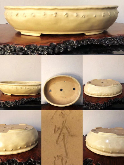 A pale yellow glazed ceramic pot with raised dots and carved characters on its base.