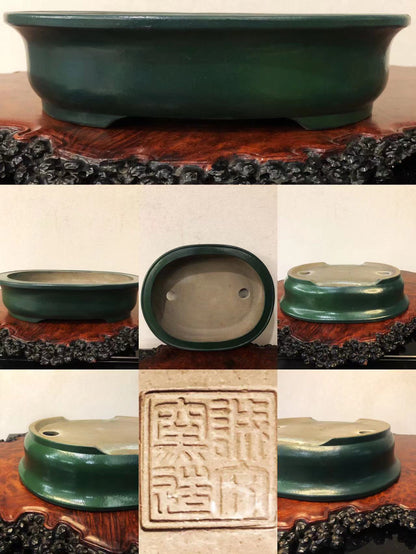 Dark green glazed pot with two drainage holes and a square seal impression.
