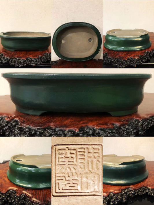 Dark green glazed pot with two drainage holes and a square seal impression.