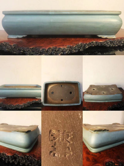 A light blue glazed rectangular pot with four feet and an engraved mark on its base.