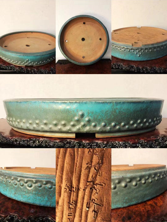 A turquoise glazed pot with raised dots, unglazed interior, and carved characters on its base.