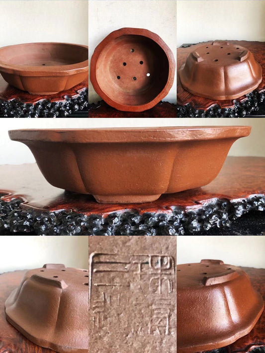 A terracotta bonsai pot with fluted sides, drainage holes, and an impressed maker’s mark.