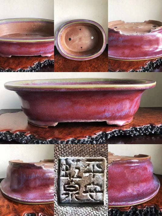 A glossy, deep red glazed ceramic pot with a square seal mark and drainage holes.