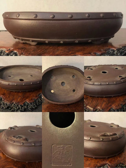 Dark brown glazed pot with rivet-like bumps around rim and three drainage holes on base.