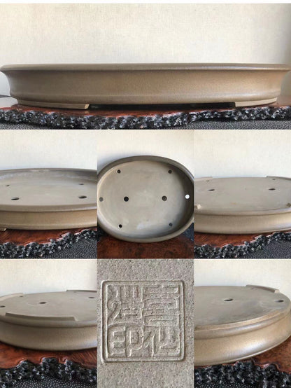 A matte grey ceramic bonsai pot with a square seal mark and drainage holes.