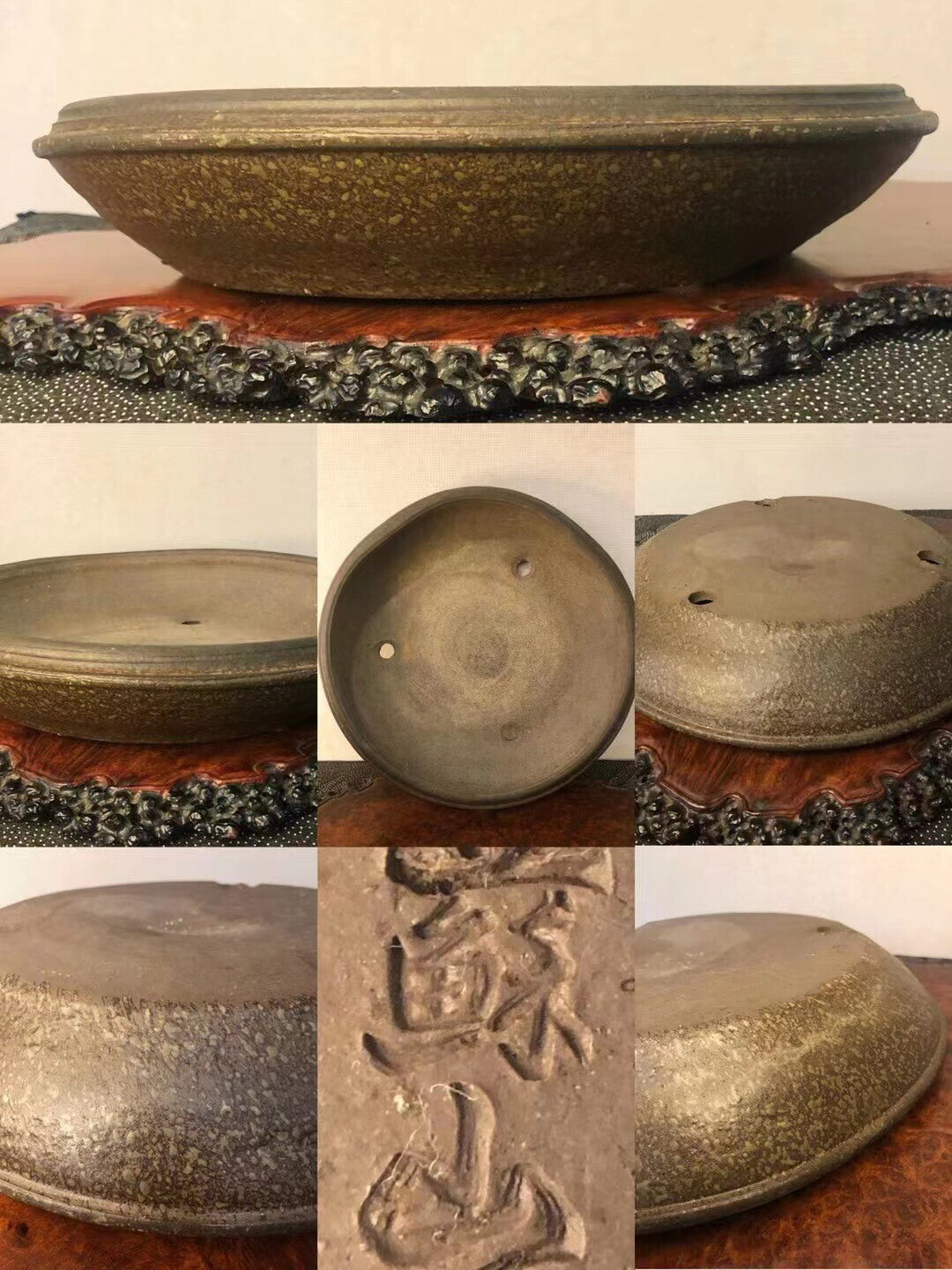A dark, speckled glazed pot with three drainage holes and carved characters on its base.