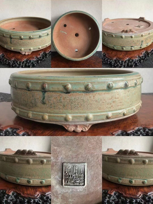 A green glazed ceramic pot with raised bumps and a square maker's mark.
