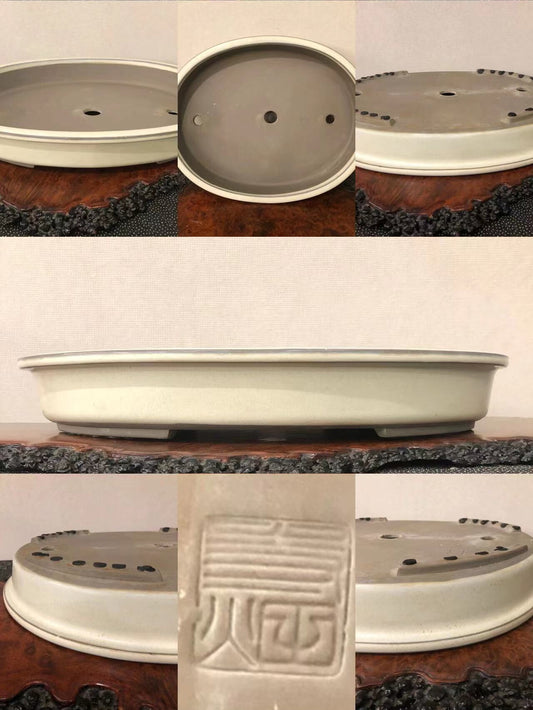 A light grey glazed bonsai pot with a single carved seal mark on its base.
