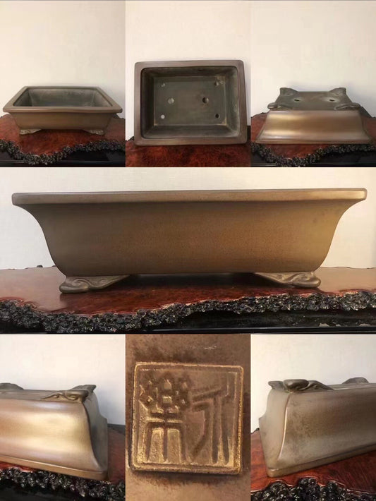 A rectangular bronze pot with a brushed finish, featuring a raised square seal on its side.