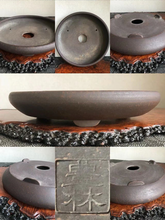 Dark brown glazed ceramic bonsai pot base with three drainage holes and a carved seal.