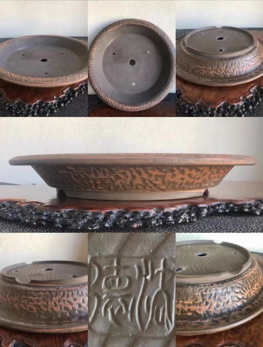 A dark brown glazed ceramic bonsai pot with carved patterns and a visible maker's mark.