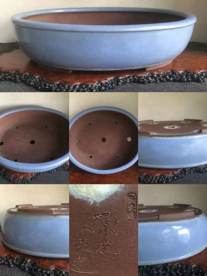 Light blue glazed ceramic bonsai pot with brown rim and base, showing drainage holes and maker's mark.