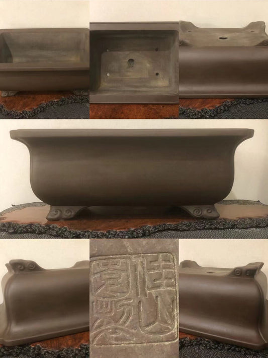 Dark brown glazed rectangular pot with carved character marks and four ornate feet.