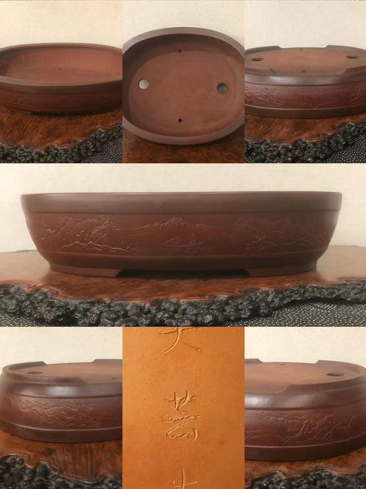 A dark brown glazed ceramic bonsai pot with carved mountain scenes and three drainage holes.