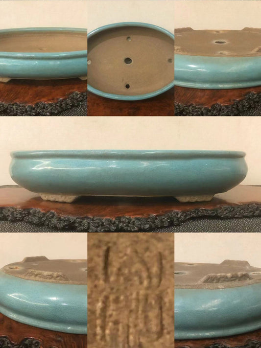 A glossy turquoise glazed pot with three drainage holes and a carved mark on its base.