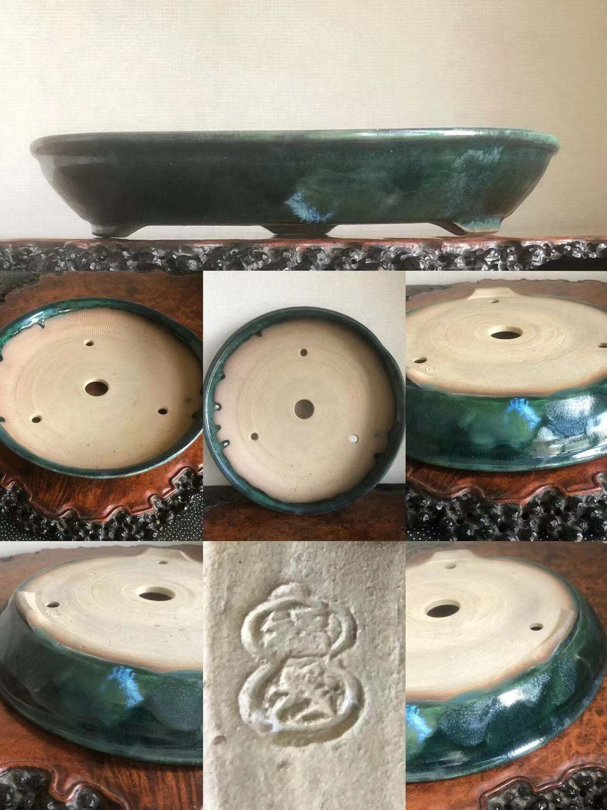 A dark green glazed bonsai pot with a light beige interior and a carved emblem on its base.