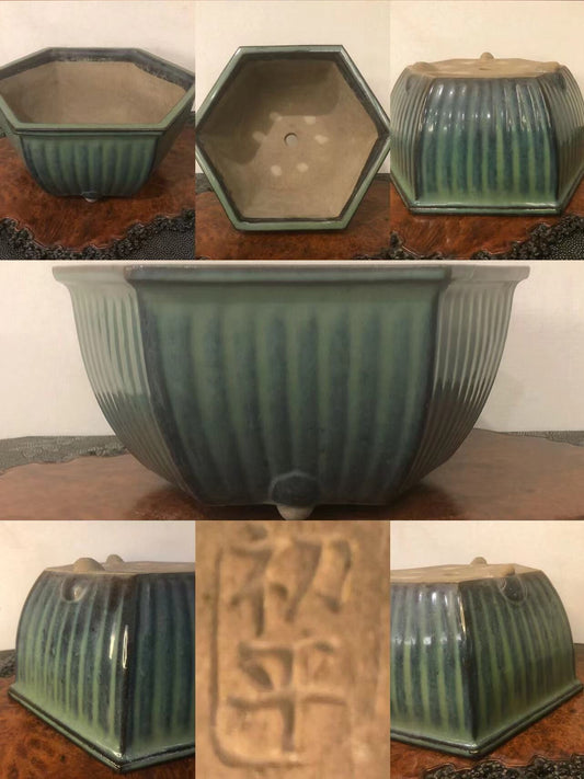 A hexagonal glazed pot with vertical ridges and a stamped character on its base.