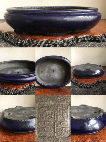A dark blue glazed pot with a wide rim and three drainage holes, showing an impressed seal.
