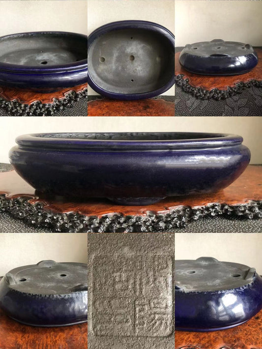 A dark blue glazed pot with a wide rim and three drainage holes, showing an impressed seal.