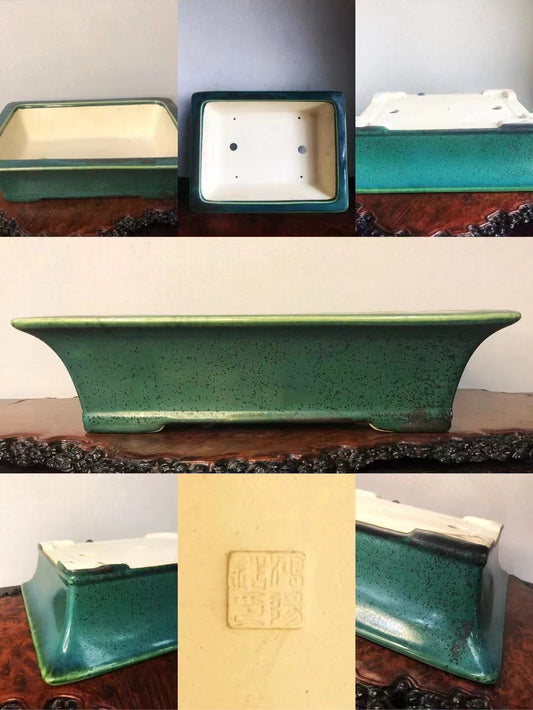 A green speckled glazed rectangular pot with a cream interior and a square maker's mark.