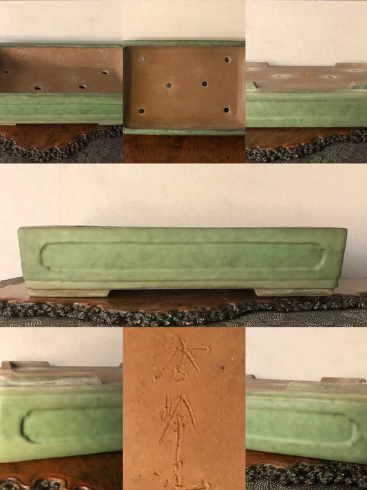 Rectangular green glazed pot with carved characters and drainage holes on base.