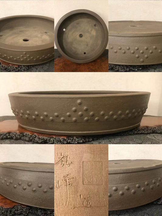 Dark brown glazed pot with raised dot pattern and carved characters on its base.